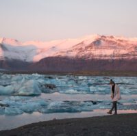 a traveler walking on the beach of Jokulsarlon Glacier Lagoon in winter at sunset