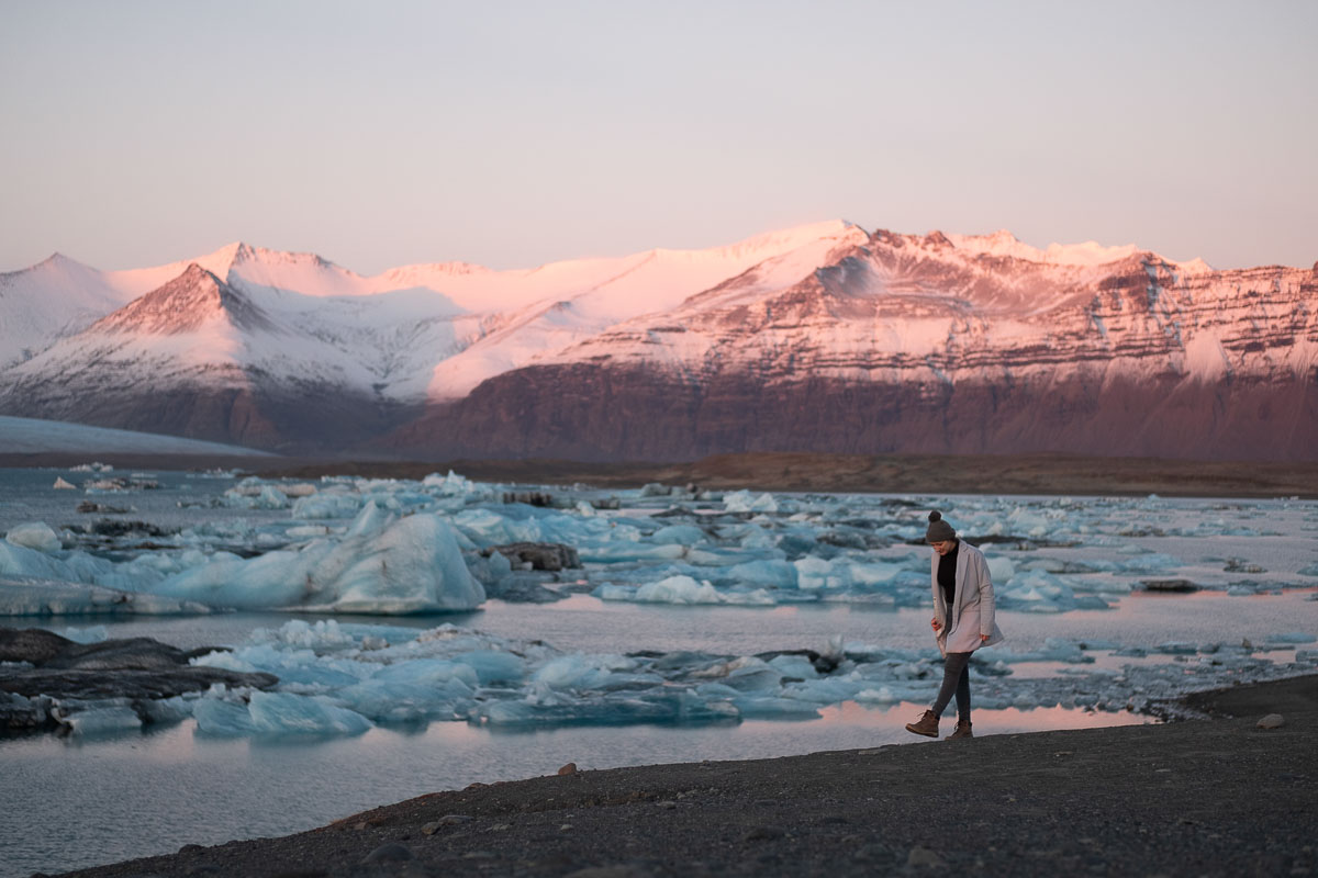 a traveler walking on the beach of Jokulsarlon Glacier Lagoon in winter at sunset