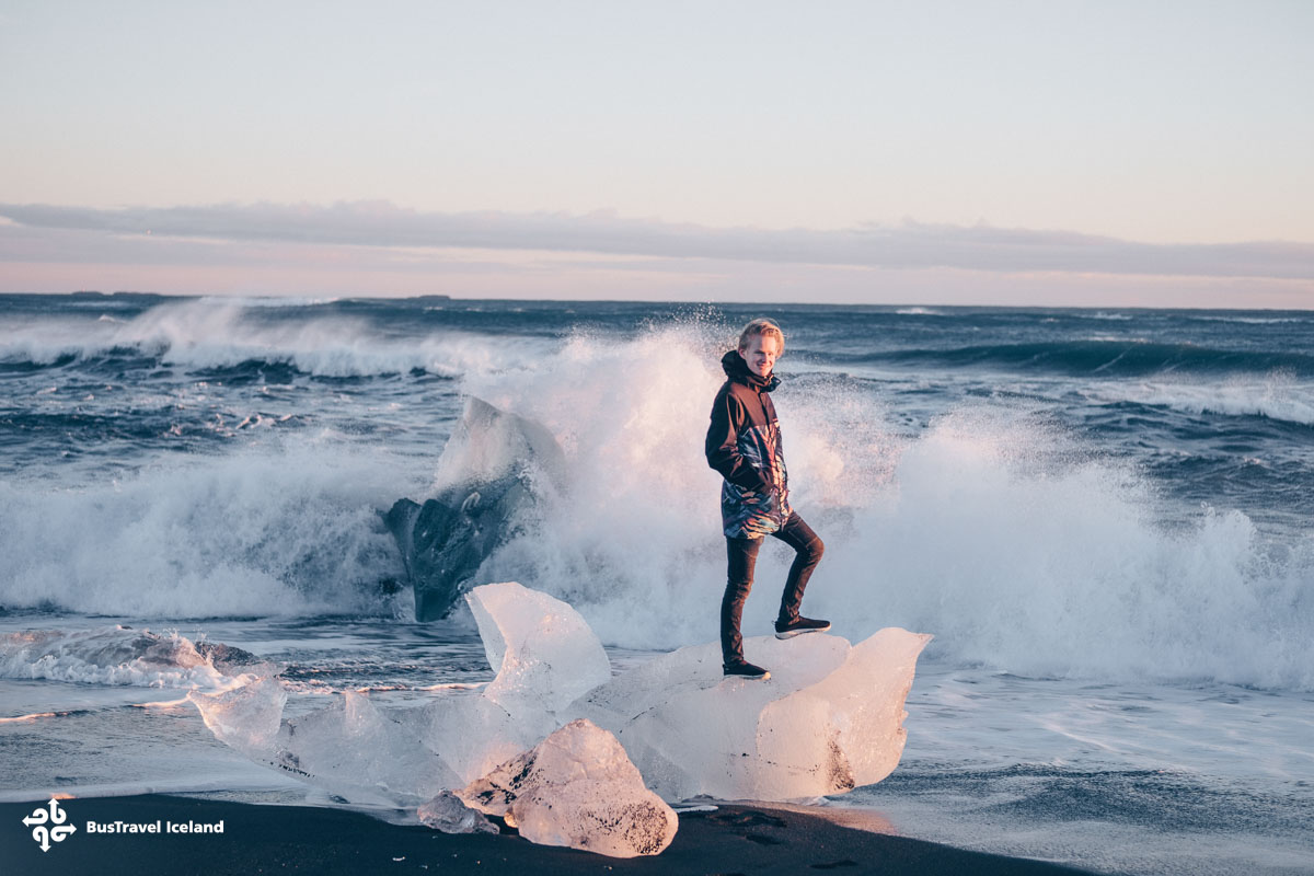 A man on an iceberg at the Diamond Beach