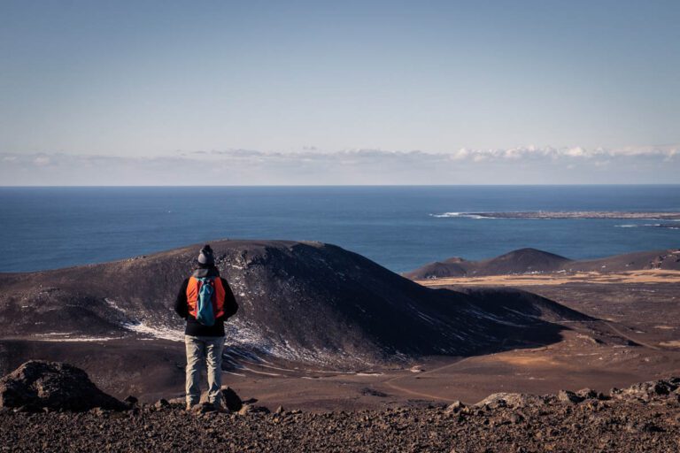 A hiker enjoying the view from a mountain slope on a volcano hike