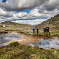 People standing near geothermal hot springs and mud pools