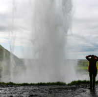 A woman standing bihind Seljalandsfoss waterfall