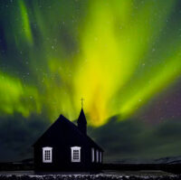 Green Northern Lights over a black church