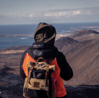 A hiker with a backpack enjoying the scenery at Fagradalsfjall volcano from a mountain hill