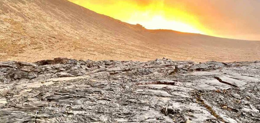 Warm light of sunset spreading over volcano eruption site